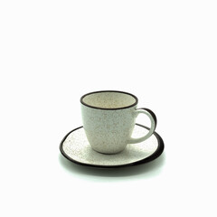 Beige porcelain cup and saucer with small brown dots and rims. Side view. Isolated over white background.