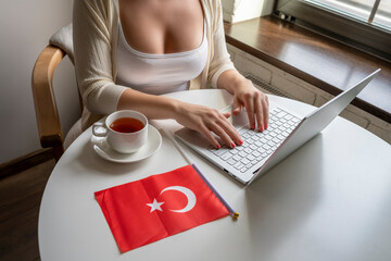 Lonely woman freelancer with Turkish flag enjoying having breakfast with cup of coffee working on...