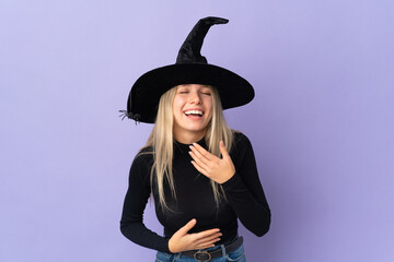 Young woman with witch costume over isolated background smiling a lot