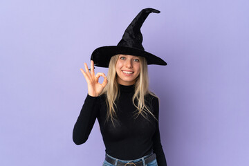 Young woman with witch costume over isolated background showing ok sign with fingers