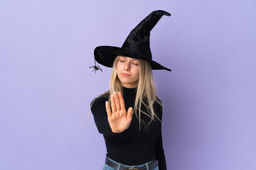 Young woman with witch costume over isolated background making stop gesture and disappointed