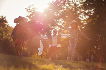 Obraz na płótnie Canvas Little girls in Halloween suits walking together trough park.