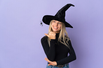 Young woman with witch costume over isolated background pointing to the side to present a product