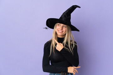 Young woman with witch costume over isolated background pointing to the side to present a product