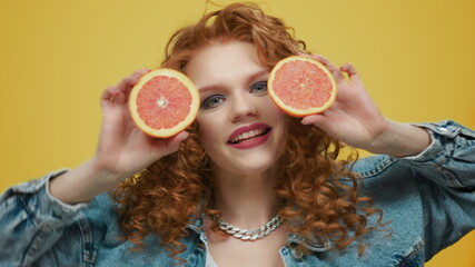 Woman holding grapefruit pieces. Girl covering face with grapefruit halves