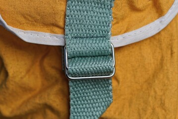 metal carabiner rings with green straps on the brown fabric of the backpack