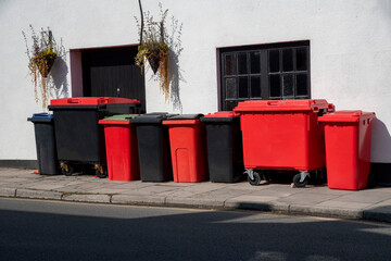 UK. 2020.  Black and red recycling bins against a pub wall  wait for empying.