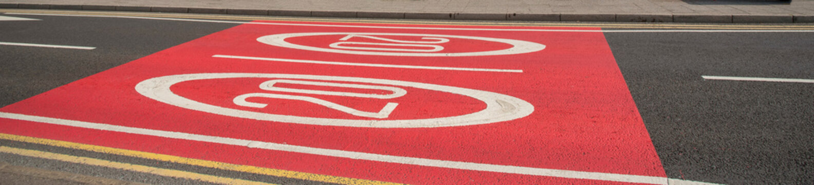 UK. 2020. Highway with brightly painted 20mph signs in red and white on the street.