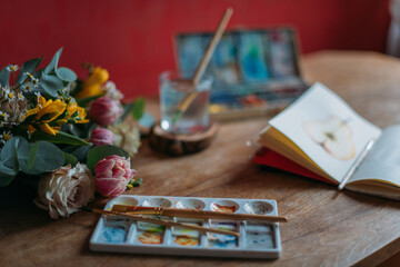 Artist's desktop with watercolors, palette, sketchbook