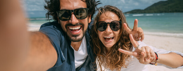A pair of lovers take a selfie on a tropical beach.