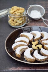 Putri Salju Kacang Mede or crescent-shaped cookies with cashew coated with powdered sugar. Popular Indonesian dessert to celebrate Eid al Fitr or Idul Fitri. Dark brown background