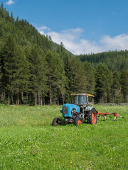 Vintage tractor on a green meadow in front of a mountain forest. Scene near L&auml;ngenfeld, Tyrol, Austria