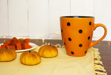 pumpkin-shaped pastries on the table next to the cup