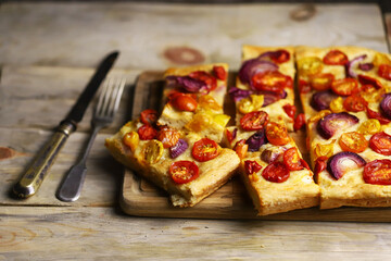 Selective focus. Homemade focaccia with cherry tomatoes and blue onions.
