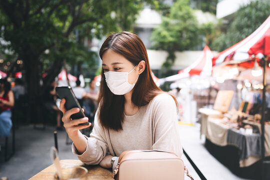 Adult asian female with protective face mask for virus corona using mobile phone application.