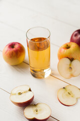 apple juice in a glass and apples on wooden background. Healthy apple juice drink and red apples fruits in autumn