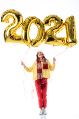 pleased woman in santa hat and scarf holding balloons with 2021 numbers isolated on white