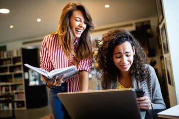 Group of happy students reading books and preparing to exam in library