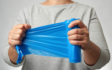 woman holding a roll of blue garbage bags in her hand
