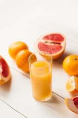 Mix of fresh citrus fruits. Glass of juice and citrus with leaves on white background.