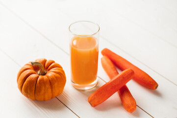 Pumpkin and Carrot smoothie in white wooden background. close-up view of natural fresh smoothies in glasses and ingredients on table