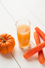 Pumpkin and Carrot smoothie in white wooden background. close-up view of natural fresh smoothies in glasses and ingredients on table