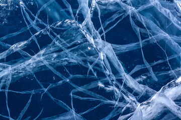 Strips of cracks in the clear blue ice. Beautiful patterns. Horizontal.