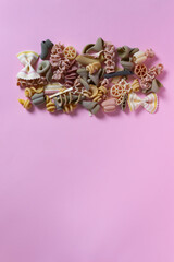 Italian pasta of different shapes and colors on a pink background. Copy space. Selective focus. Top view. Vertical orientation.