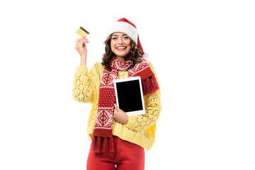 joyful woman in santa hat and scarf holding digital tablet with blank screen and credit card isolated on white