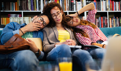 Obraz premium College, study, university and education concept. Group of tired students learning in library