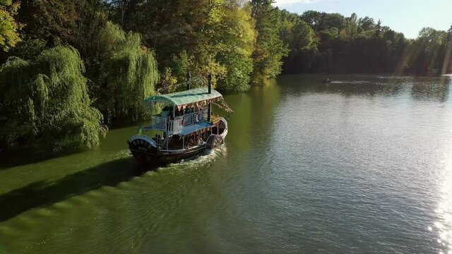 Autumn, a pleasure boat rolls tourists around the lake. Sofievsky Park, Uman, Ukraine. Port, blue.