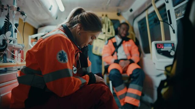 Tired Female EMS Professional Paramedic Tries to Rest in an Ambulance Vehicle on the Way to Emergency. Emergency Medical Technicians are on Their Way to a Call Outside the Healthcare Hospital.