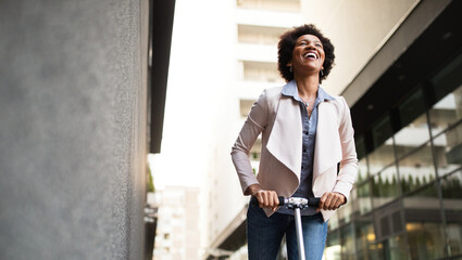 Happy woman on the electric scooter with background of office building © NDABCREATIVITY