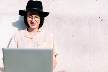 woman working with computer sitting against a wall