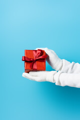 partial view of young woman in gloves holding gift box on blue