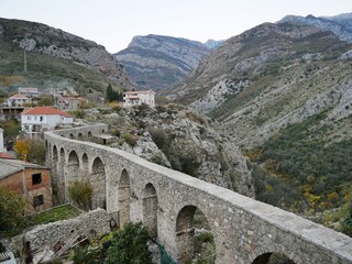 Fototapeta na wymiar Winding old viaduct set against striped mountains and houses with tiled roofs