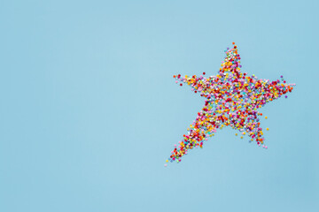 creative christmas concept: star made of colorful mini stars on blue background