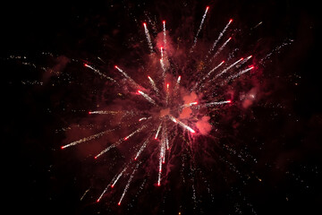 Red explosion of fireworks with smoke and bokeh on a black background.