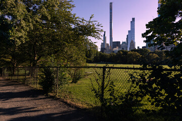 Fence and a Midtown Manhattan Skyline View with the Sheep Meadow at Central Park during Summer in New York City
