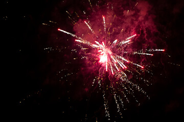 Red explosion of fireworks with smoke and bokeh on a black background.