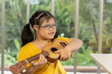 Autistic, Autism or Down Syndrome children girl is playing the ukulele. Concept disabled child learning in school.