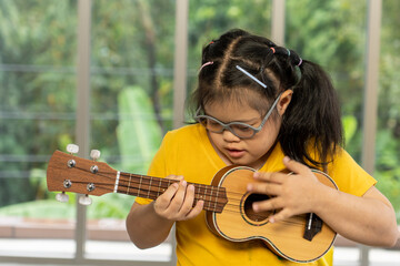 Autistic, Autism or Down Syndrome children girl is playing the ukulele. Concept disabled child...
