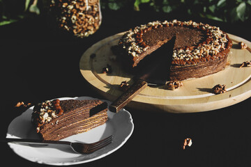 Chocolate pancake cake with nuts. Pie close-up. Cake on black background