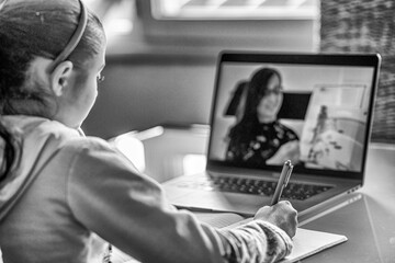 Schoolgirl studying homework during her online lesson at home, social distance during quarantine, self-isolation, online education concept, home schooler
