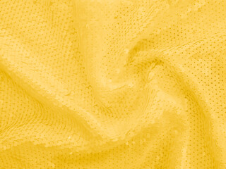 Photography of background fabric sequin in yellow color. Holiday abstract glitters with blinking lights. Fashion fabric.