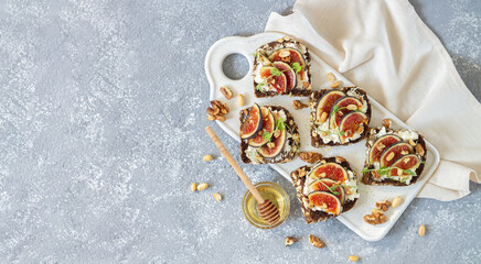 Toast with fresh figs, ricotta, nuts and honey on stone table