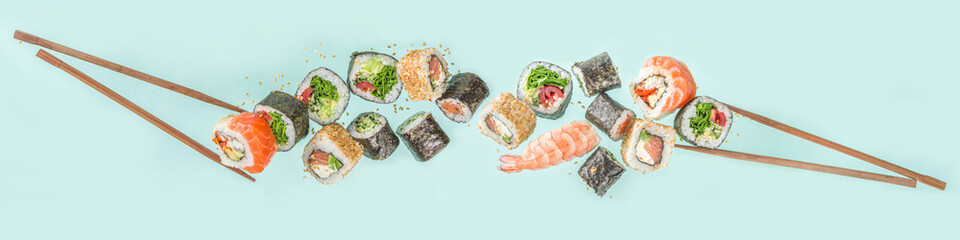 Flying sushi set with chopsticks. Various delicious japanese sushi, roll pieces and nigiri on light blue background