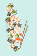 Flying sushi set with chopsticks. Various delicious japanese sushi, roll pieces and nigiri on light blue background