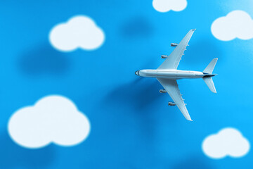 Fototapeta na wymiar Top view of a commercial plane with clouds and long shadow on a blue background.