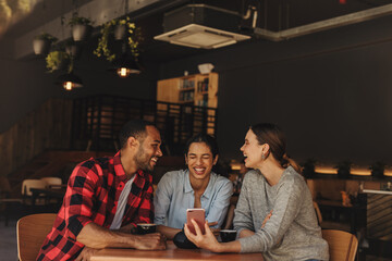 Friends at cafe watching video on a cell phone